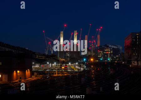 Battersea Power Station at night with the red lights of many cranes and light trails of trains going to and from Victoria Station Stock Photo