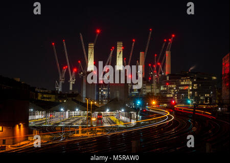 Battersea Power Station at night with the red lights of many cranes and light trails of trains going to and from Victoria Station Stock Photo