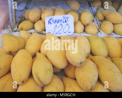 Ripe 'Nam Dok Mai' mango on sale. Sign in Thai language saying 'Nam Dok Mai 120 Baht' Stock Photo