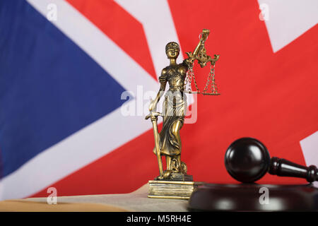 Statue  Themis on a flag of Great Britain. Judge's gavel in the background Stock Photo