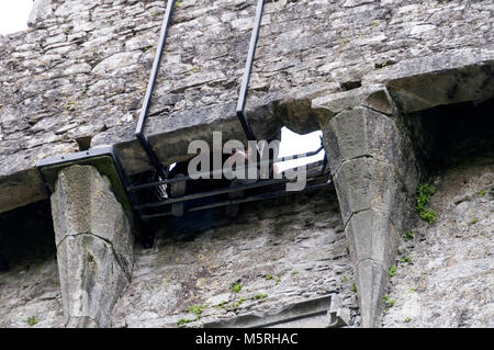 A visitor lays his/her head onto a safety grill as he/she kisses the Blarney stone high up the tower at Blarney Castle in Southern Ireland Stock Photo