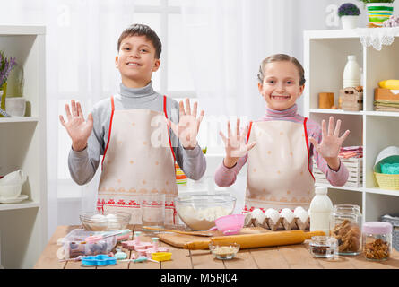 Child girl and boy cooking in home kitchen, showing hands with flour Stock Photo