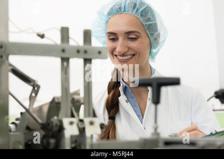 Portrait of happy woman technician checking industrial equipment Stock Photo