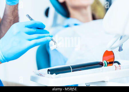 Close-up of the hand of a dentist preparing a dental LED curing  Stock Photo