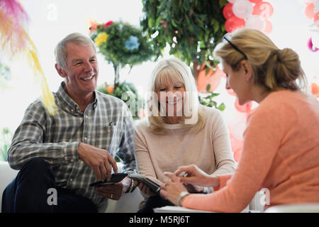Business partners are discussing their progression in the shop, using paperwork and a digital tablet. Stock Photo