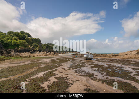 A fishing boat at low tide on the beach in the natural sheltered cove harbour of Combe Martin, a coastal village on the North Devon coast about 4 mile Stock Photo