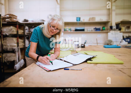 Senior businesswoman is doing paperwork in her stock factory. Stock Photo
