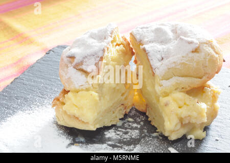 Saint John's cream puffs, backlighting on a bigne filled with cream cut in two, close up Stock Photo