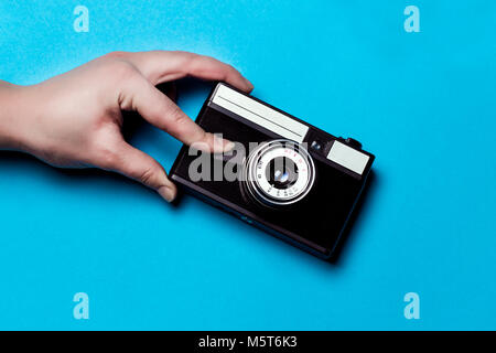 old camera on a blue background, the hand presses the shutter Stock Photo