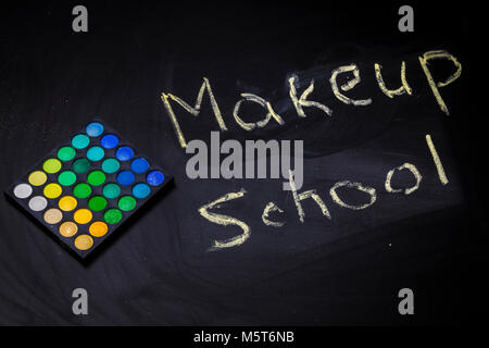 inscription makeup school on a blackboard, near palette of multi-colored shadows, concept Stock Photo