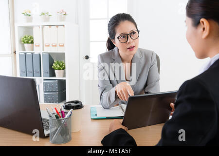 A strict business boss talking teaching blaming planning communicating with to the female employee in their office . Using holding a tablet device. Stock Photo