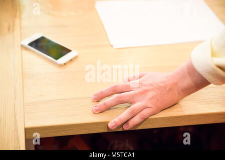 Hand leand on office desk with phone and papers Stock Photo