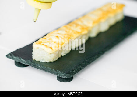 Putting sauce on uncut Japanese sushi roll Stock Photo