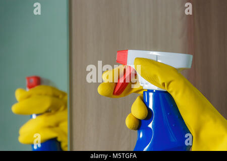 Female Hand in Yellow Glove Cleaning Mirror with Spray Cleaner. in Blue Bottle. Housework, Spring Cleaning Concept