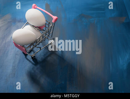 White eggs in a shopping cart, perfect Easter sale, deal, promotional background. Stock Photo