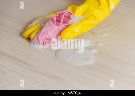 Female Hand in Yellow Glove Cleaning Light Wooden Modern Table with Pink Cloth for Home Maintenance and Housekeeping