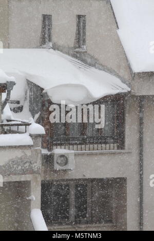 Winter. Dangerous snow falls from the roofs of the buildings. Winter with heavy snowfall. Icy roofs. Dangerous icicles above road. Snow falls above si Stock Photo