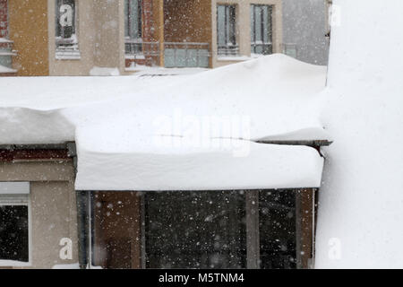 Winter. Dangerous snow falls from the roofs of the buildings. Winter with heavy snowfall. Icy roofs. Dangerous icicles above road. Snow falls above si Stock Photo