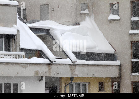 Winter. Dangerous snow falls from the roofs of the buildings. Winter with heavy snowfall. Icy roofs. Dangerous icicles above road. Snow falls above si Stock Photo