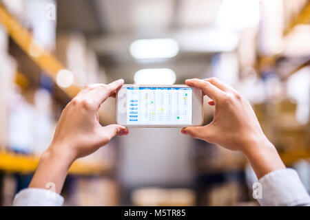 Woman warehouse worker with smartphone. Stock Photo