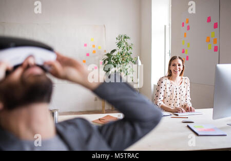 Two business people with wheelchair and VR goggles in the office. Stock Photo