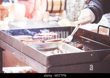 Close up hands holding homemade sausage roasted on a grill, selective focus and small depth of field Stock Photo