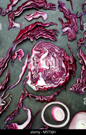 Arrangement of colorful red cabbage and red onion on slate table Stock Photo