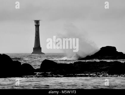 Stormy seas with big waves breaking against rocks, black and white. Bishop Rock, Isles of Scilly, United Kingdom