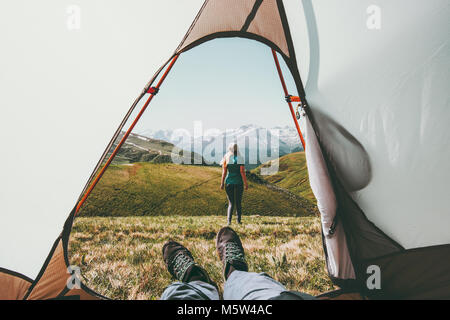 Travel camping couple view from tent entrance woman walking in mountains man feet relaxing inside Lifestyle concept adventure summer vacations outdoor Stock Photo