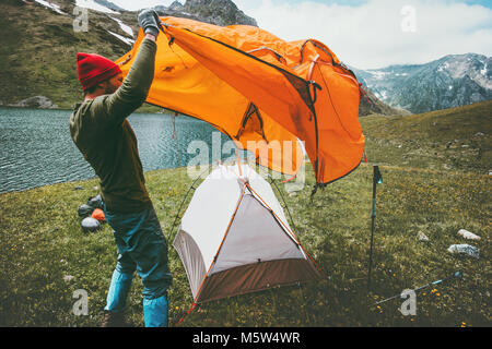 Man Traveler pitching tent camping gear outdoor Travel adventure lifestyle concept summer journey vacations in mountains Stock Photo