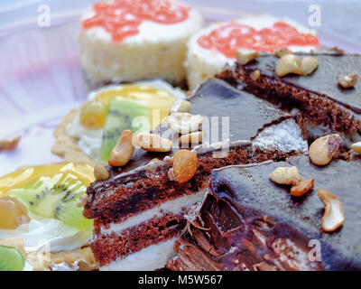 Big slice of the chocolate cake with nuts on the dessert table close-up Stock Photo