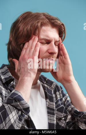 man having headache. Isolated over blue background. Stock Photo