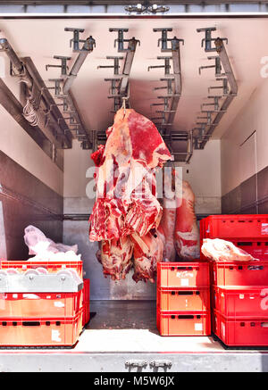 Food delivery of raw beef or pork, half beef in a cooling truck. Fresh red meat, buttery or slaughter house theme. Meat transporter, food industry. Stock Photo