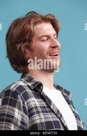 The happy businessman standing and smiling against blue background. Stock Photo