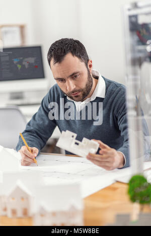 Pleasant engineer making corrections in blueprint Stock Photo