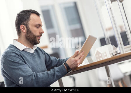 Bristled young man working on tablet in office Stock Photo