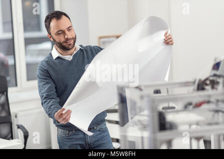 Handsome engineer examining blueprint in his hands Stock Photo