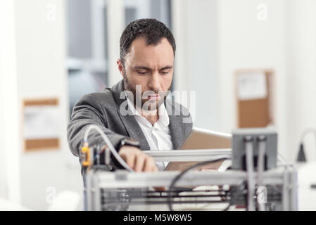Young engineer fixing problems with 3D printer Stock Photo