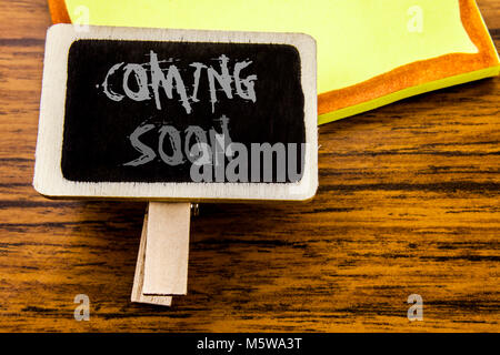 Handwritten text showing Coming Soon. Business concept for Under Construction written on announcement board on wooden wood background. Stock Photo