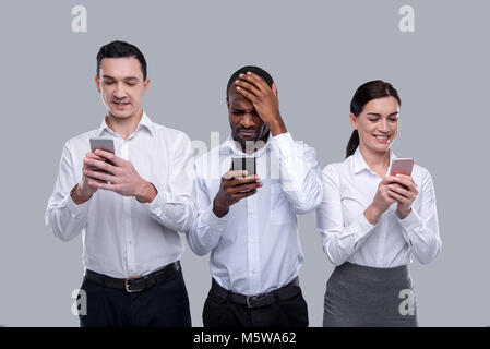 Three colleagues typing on their phones Stock Photo