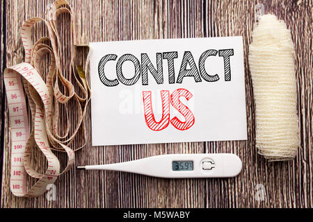 Handwritten text showing Contact Us. Business fitness health concept writing for Customer Support written on wood wooden background with bandage and t Stock Photo