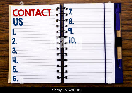 Writing text showing Contact Us. Business concept for Customer Support Written on notebook paper, wooden background with pen and marker. Stock Photo