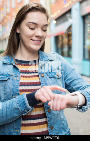 Woman Walking On City Street Using Smart Watch Stock Photo