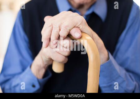 Close Up Of Senior Man’s Hands Holding Walking Cane Stock Photo