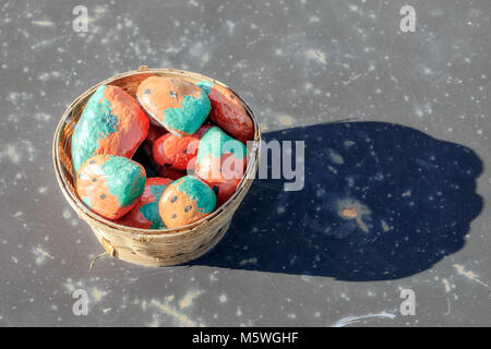 Wicker basket with decorated stones, standing on a gray plate on a bright sunny day. Stock Photo