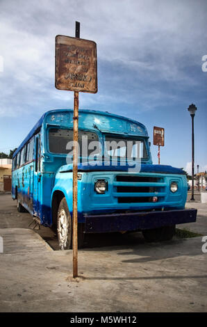 Rusty old blue coach standing next to bus stop Stock Photo