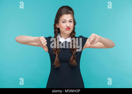 Disagree young woman demonstrate dislike sign. Indoor, studio shot on blue background Stock Photo