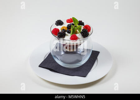 Berry and ice cream dessert in a clear glass bowl on a white plate on a white background Stock Photo