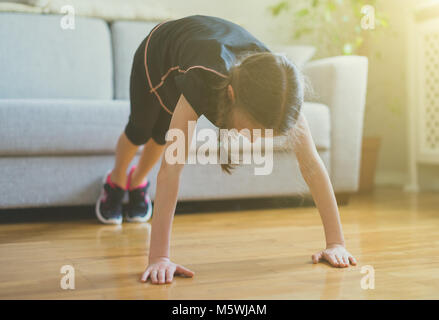 Little girl doing push ups at home. Gymnastics at home. Stock Photo