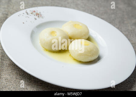 Three potato dumplings with butter on a plate Stock Photo